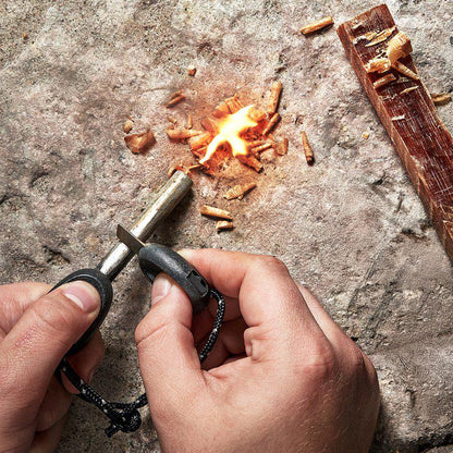 Händer slår gnistor med FireSteel Scout mot träspill på sten